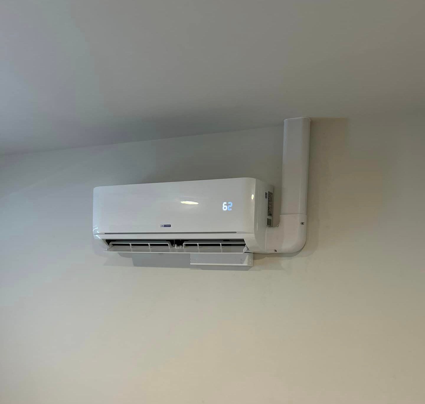 A white air conditioner is hanging from the ceiling in a room.