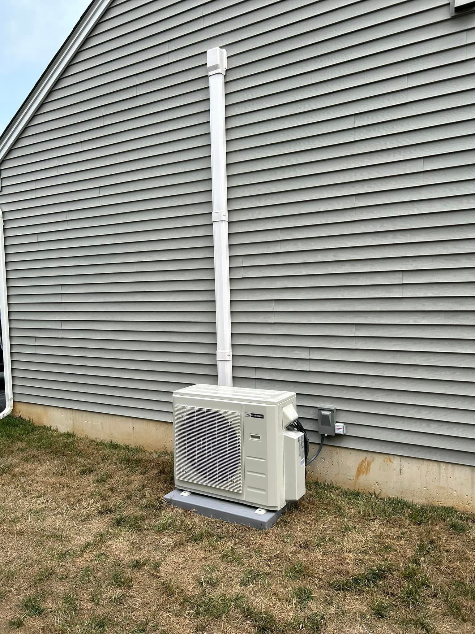 A white air conditioner is mounted on the side of a house.