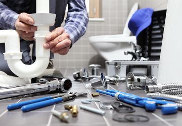 A plumber is fixing a sink in a bathroom.