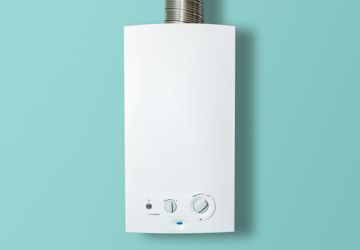 A white water heater is hanging on a blue wall.