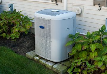 A white air conditioner is sitting on the side of a house.
