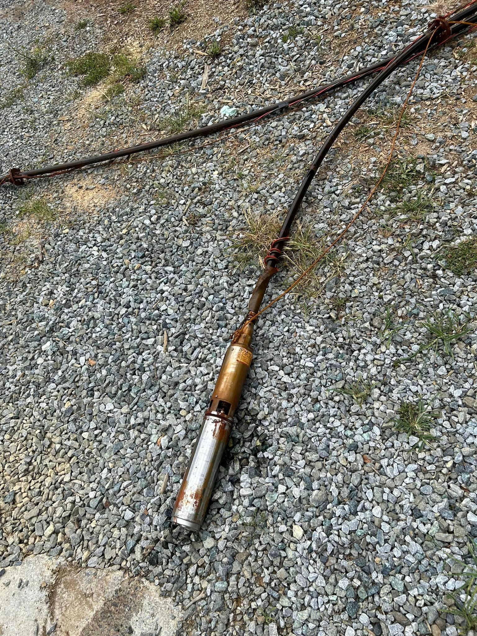 A metal object is laying on the ground next to a wire.
