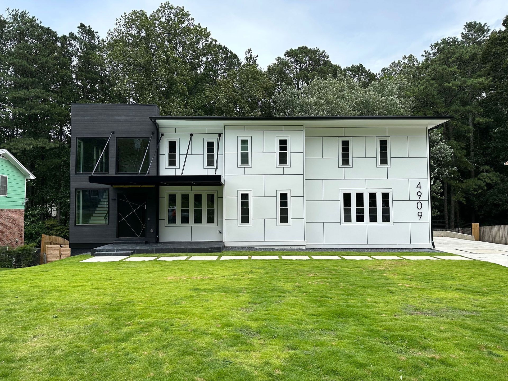 A black and white house with a large lawn in front of it