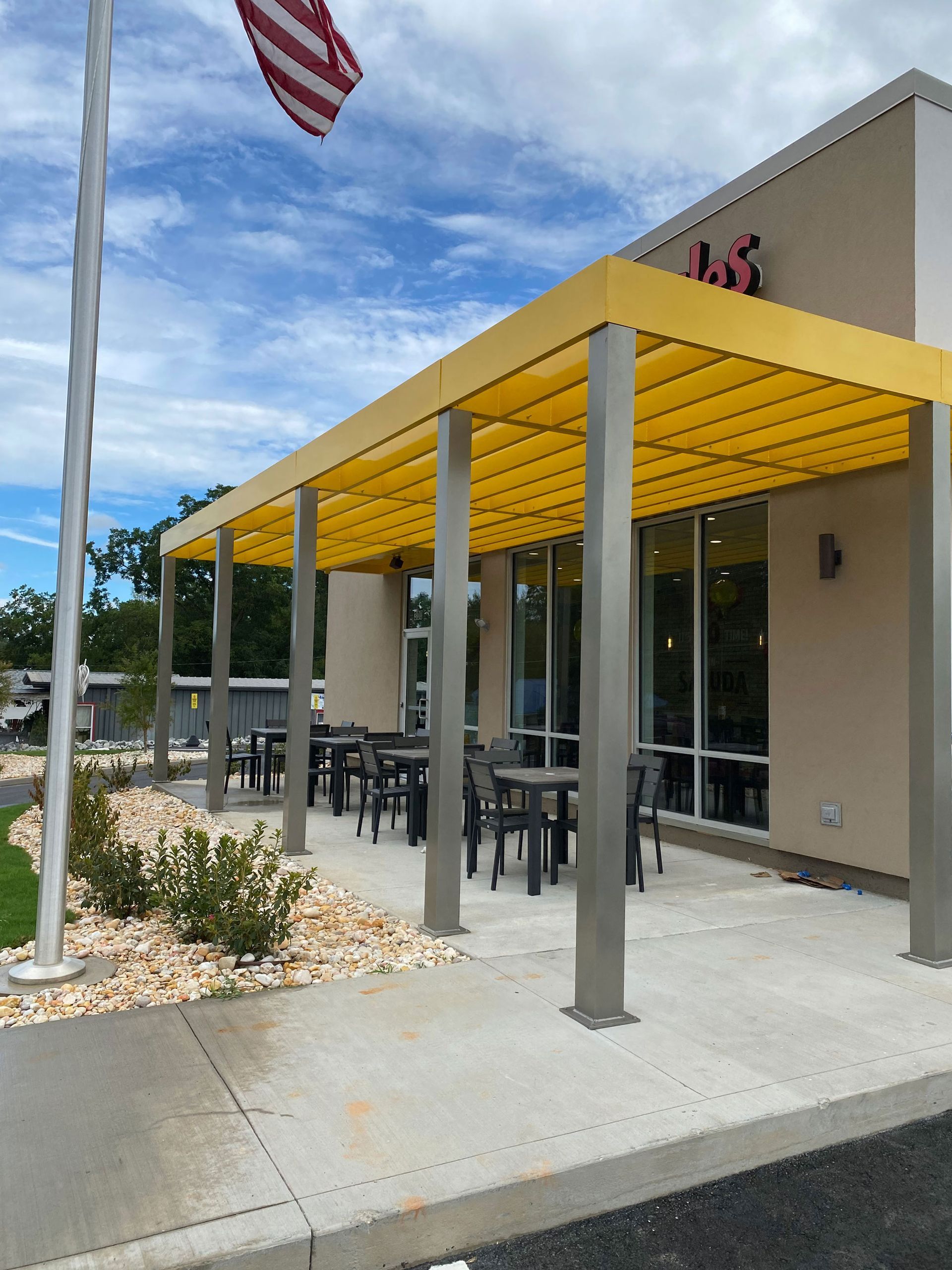 A restaurant with tables and chairs under a yellow awning