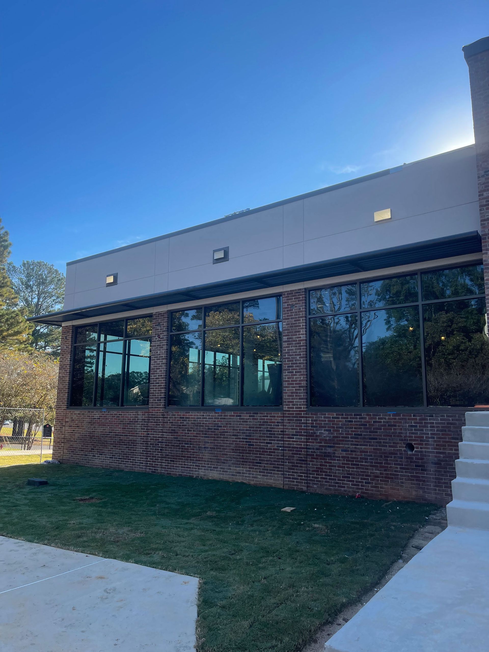 A large brick building with a lot of windows and a lawn in front of it.