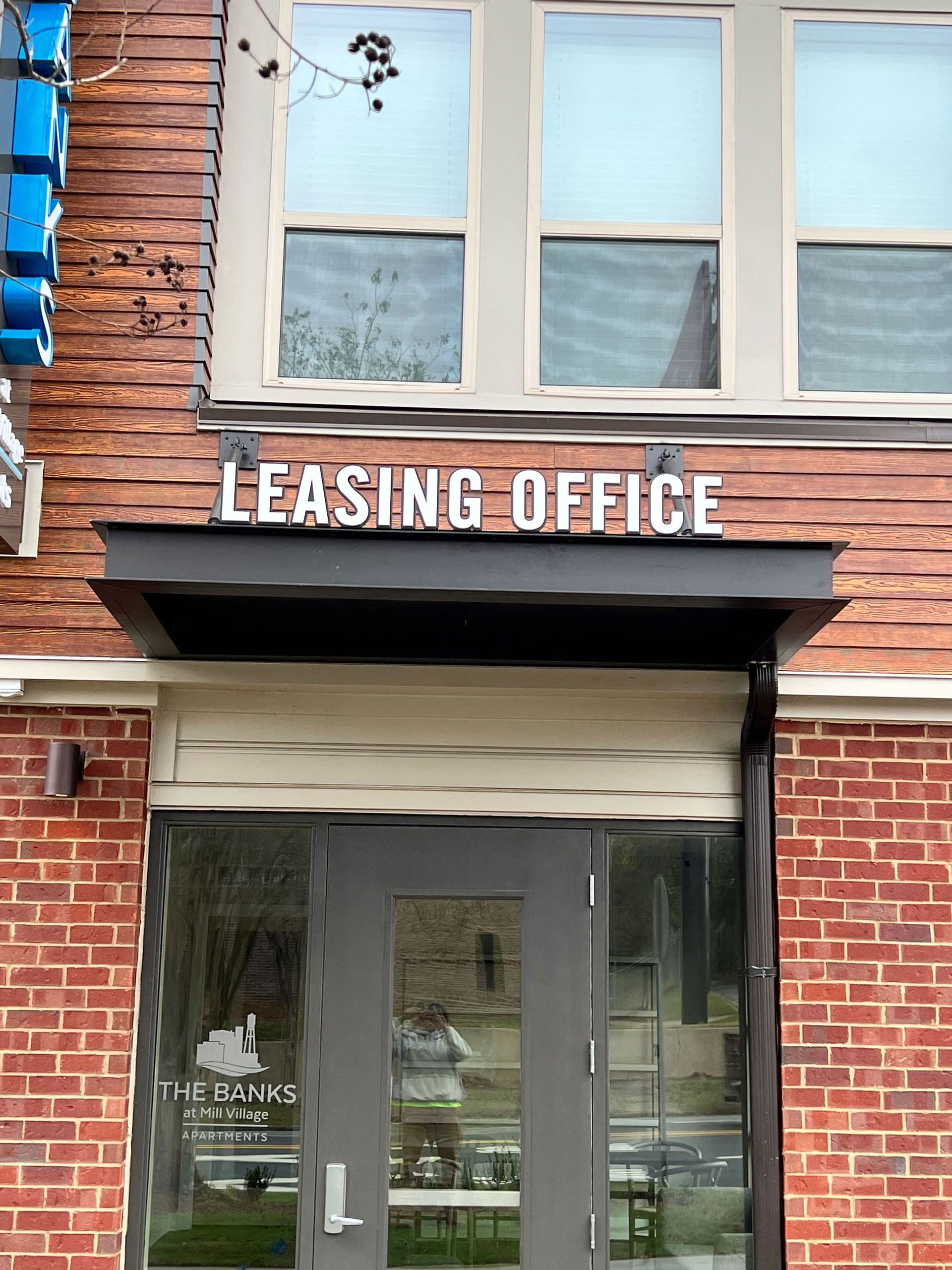 A brick building with a sign above the door that says leasing office.