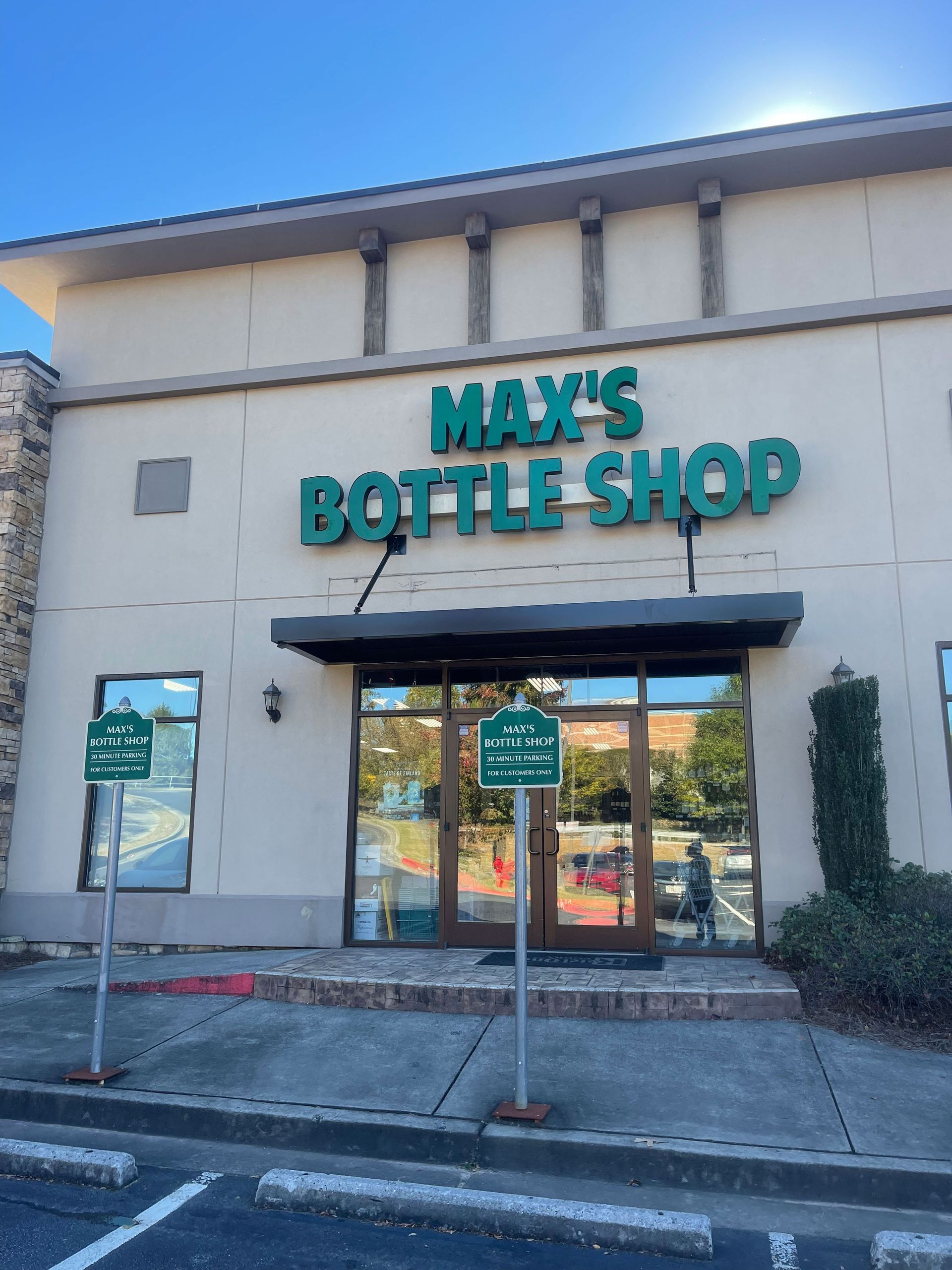 Max's Bottle Shop storefront with green sign, gray awning, and brick walkway.
