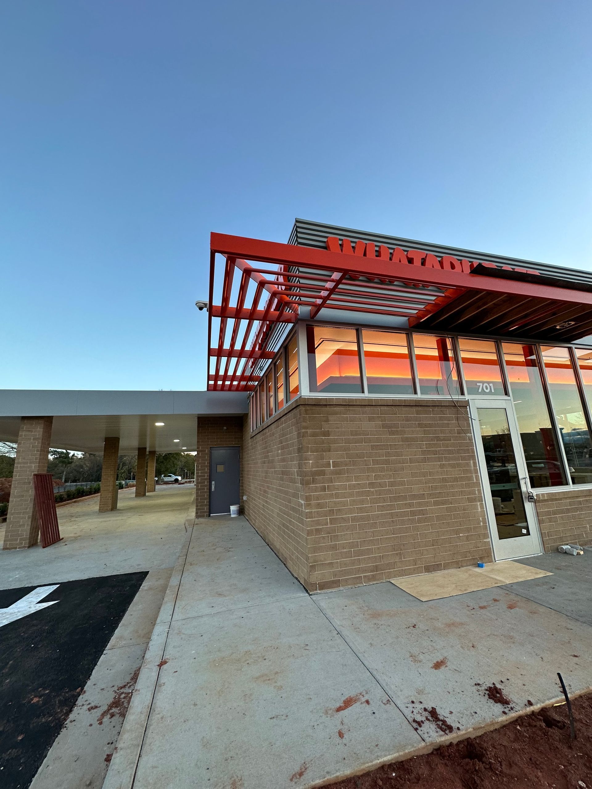 Building with red accents, brick exterior, glass windows, and a clear blue sky.