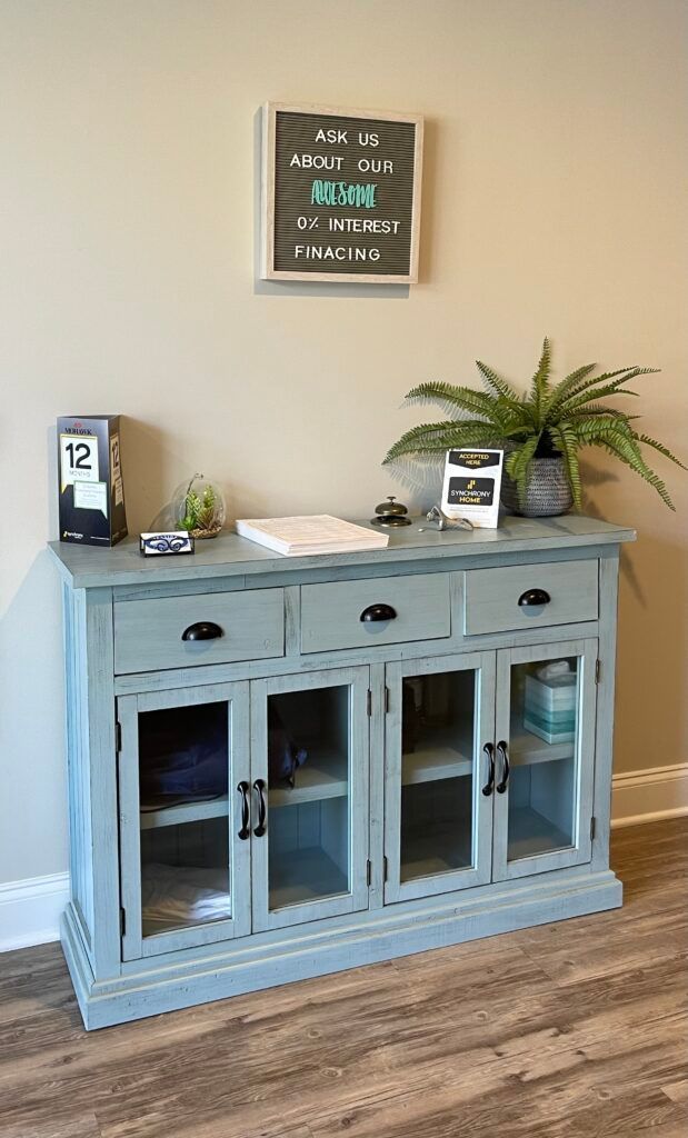 A blue cabinet with glass doors and drawers is sitting in a room next to a wall.