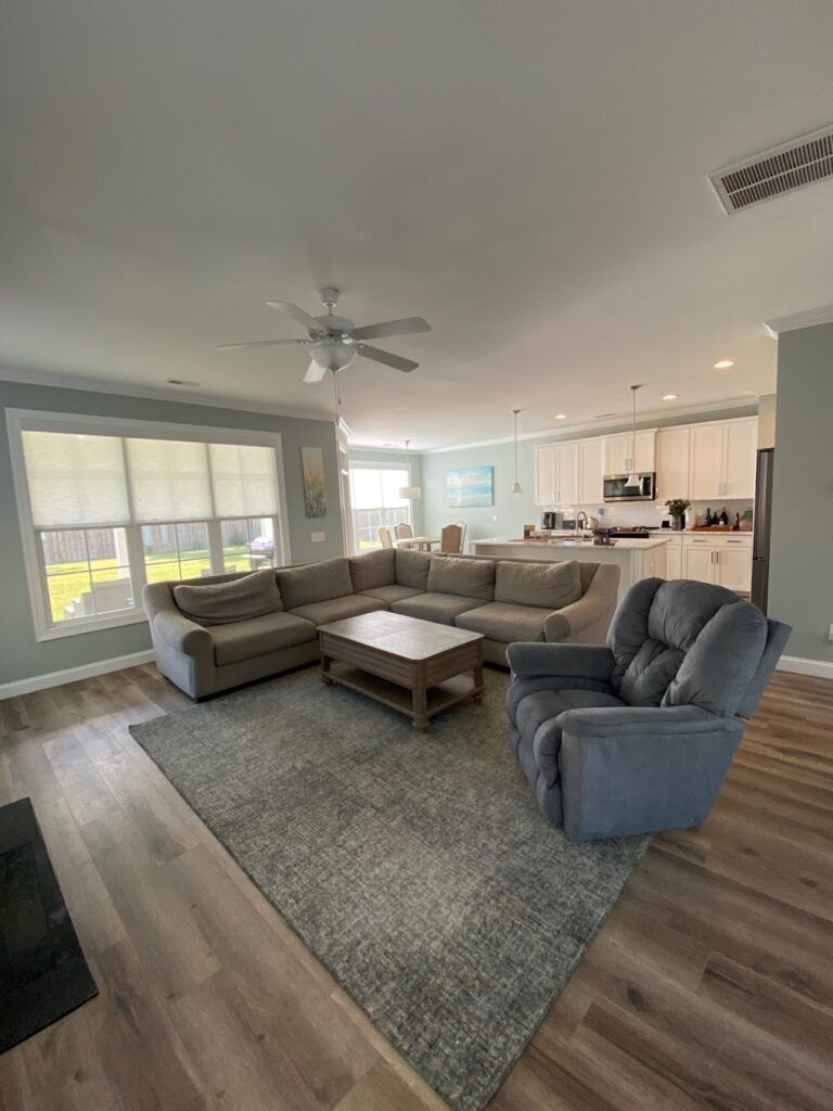 A living room with a couch , chair , coffee table and ceiling fan.
