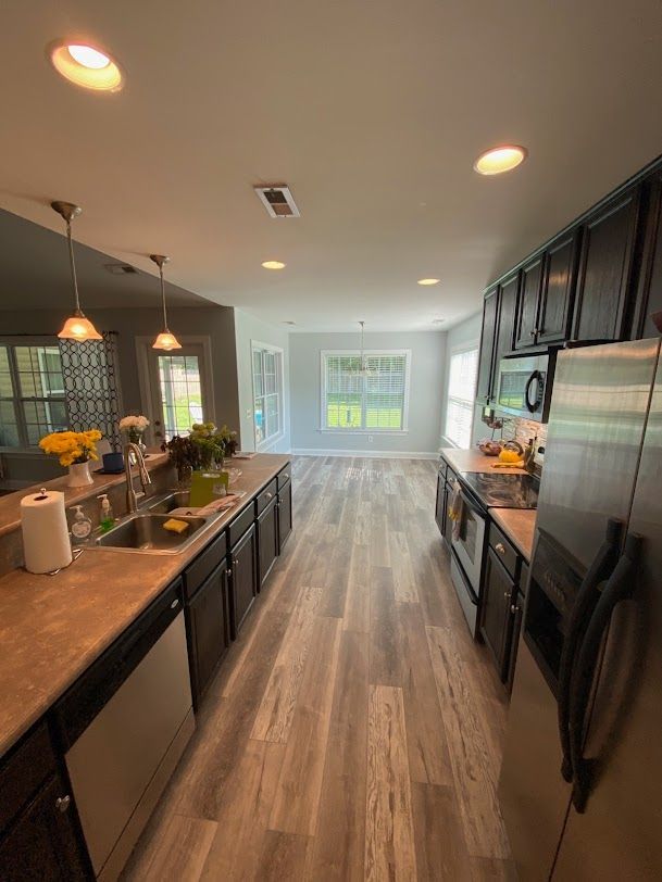 A kitchen with stainless steel appliances and wooden floors.