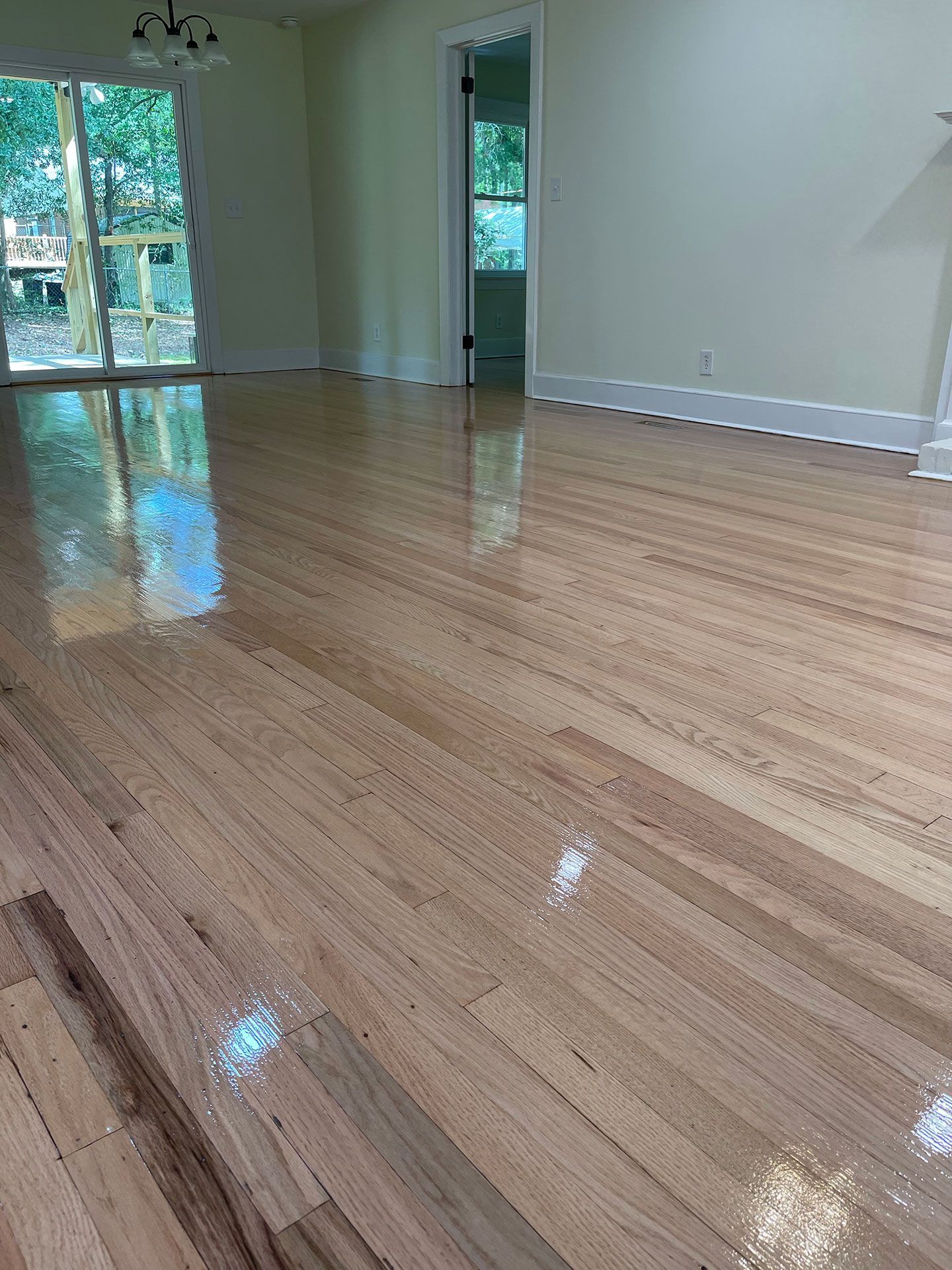 A living room with a wooden floor and a sliding glass door.