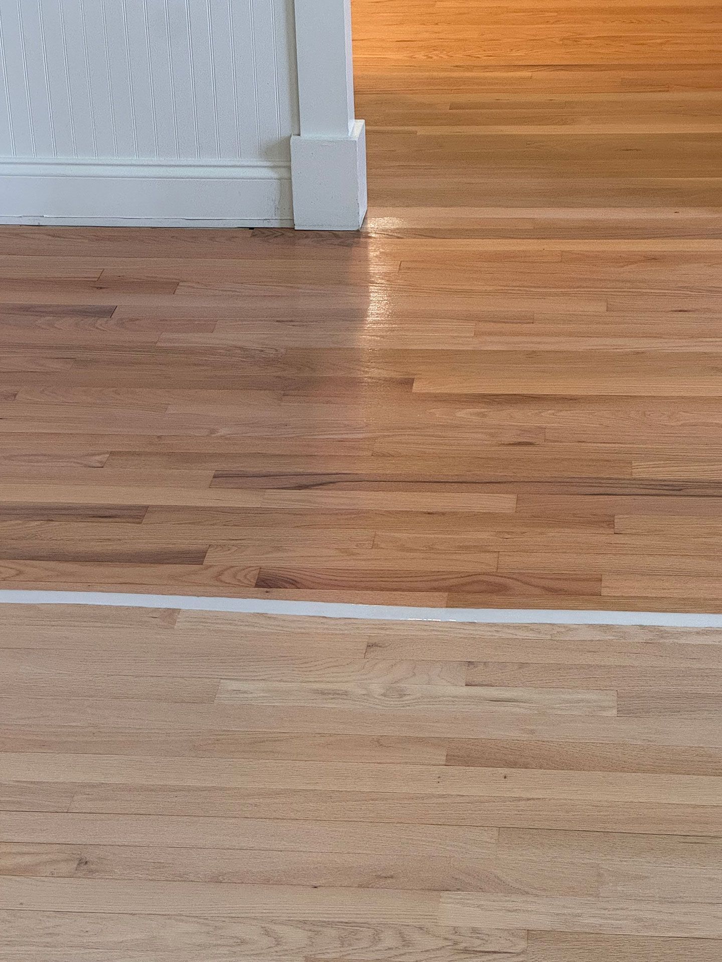A close up of a wooden floor in a room with a white wall.