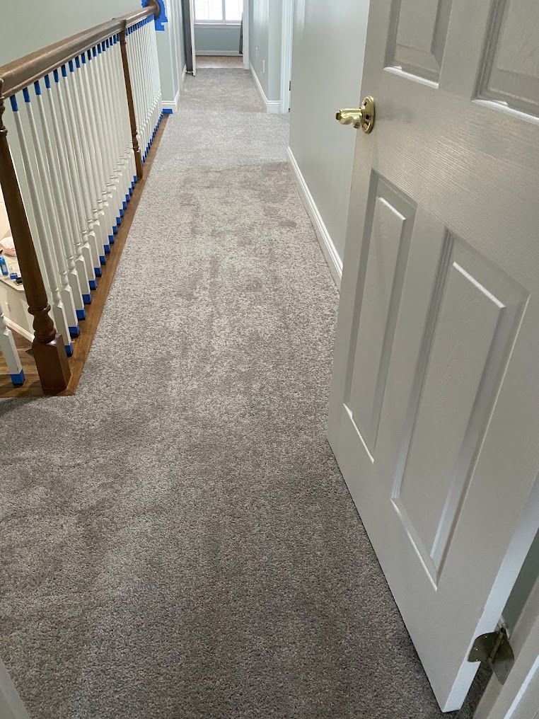 A hallway with a carpeted floor and a door leading to a staircase.
