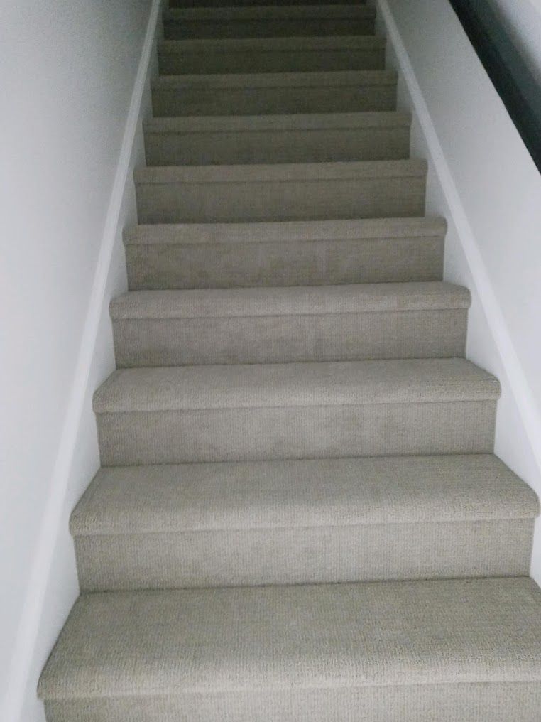 A set of stairs with carpeted steps and a white railing.