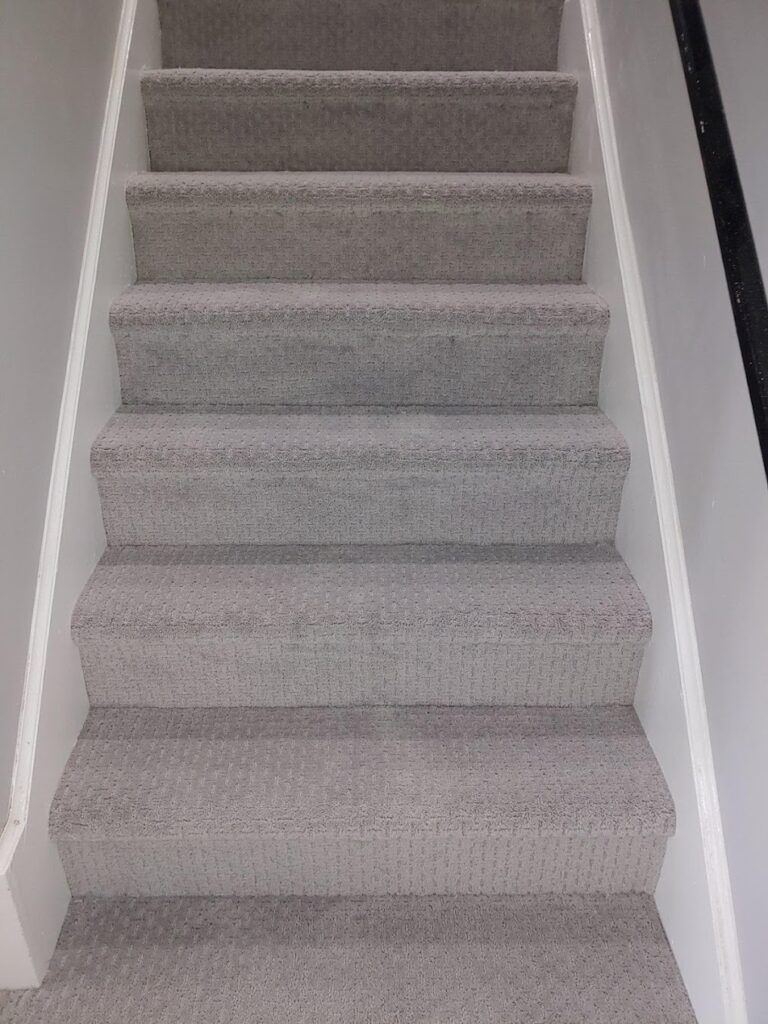 A set of stairs with carpeted steps and a white railing.