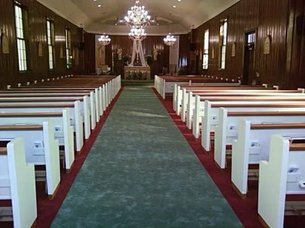 A church with rows of white benches and a green carpet