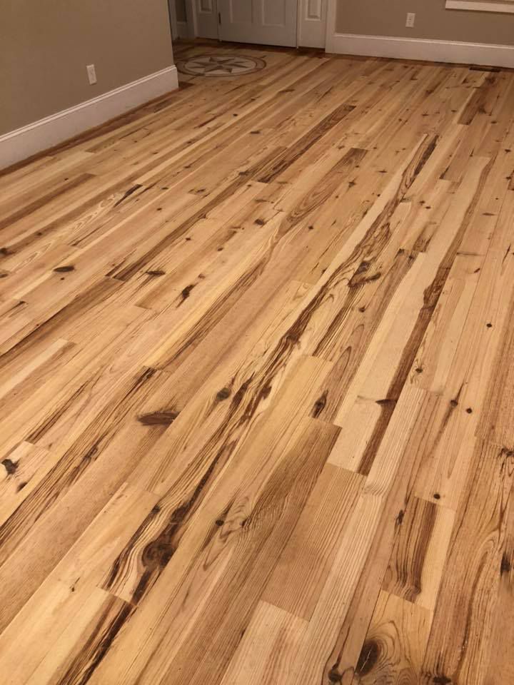 A wooden floor in a living room with a door in the background.