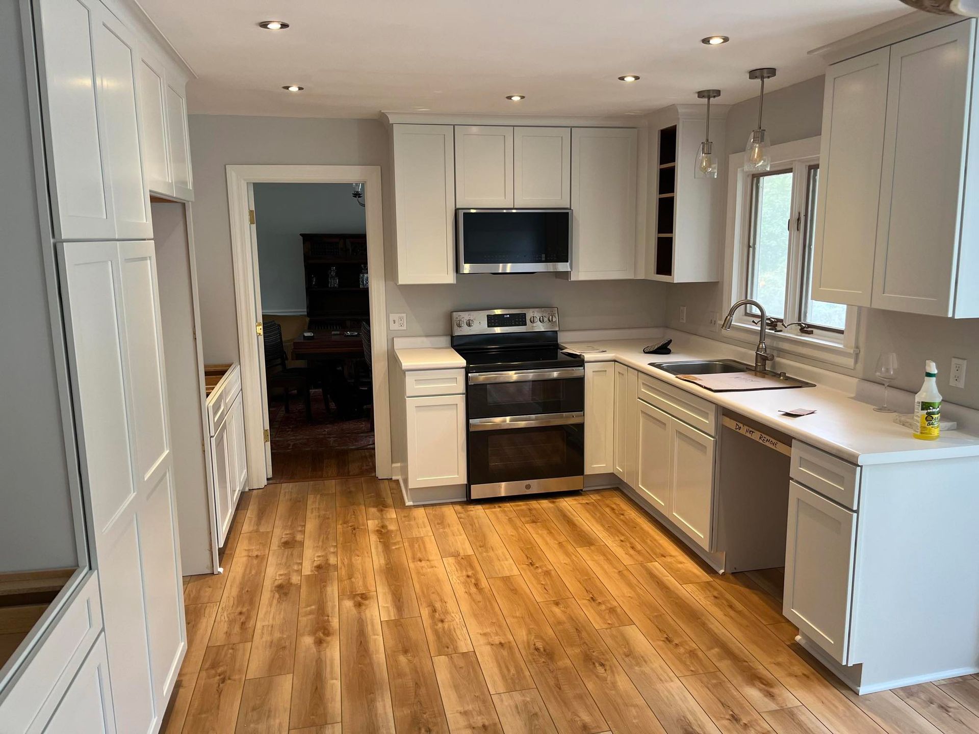 A kitchen with white cabinets and wooden floors