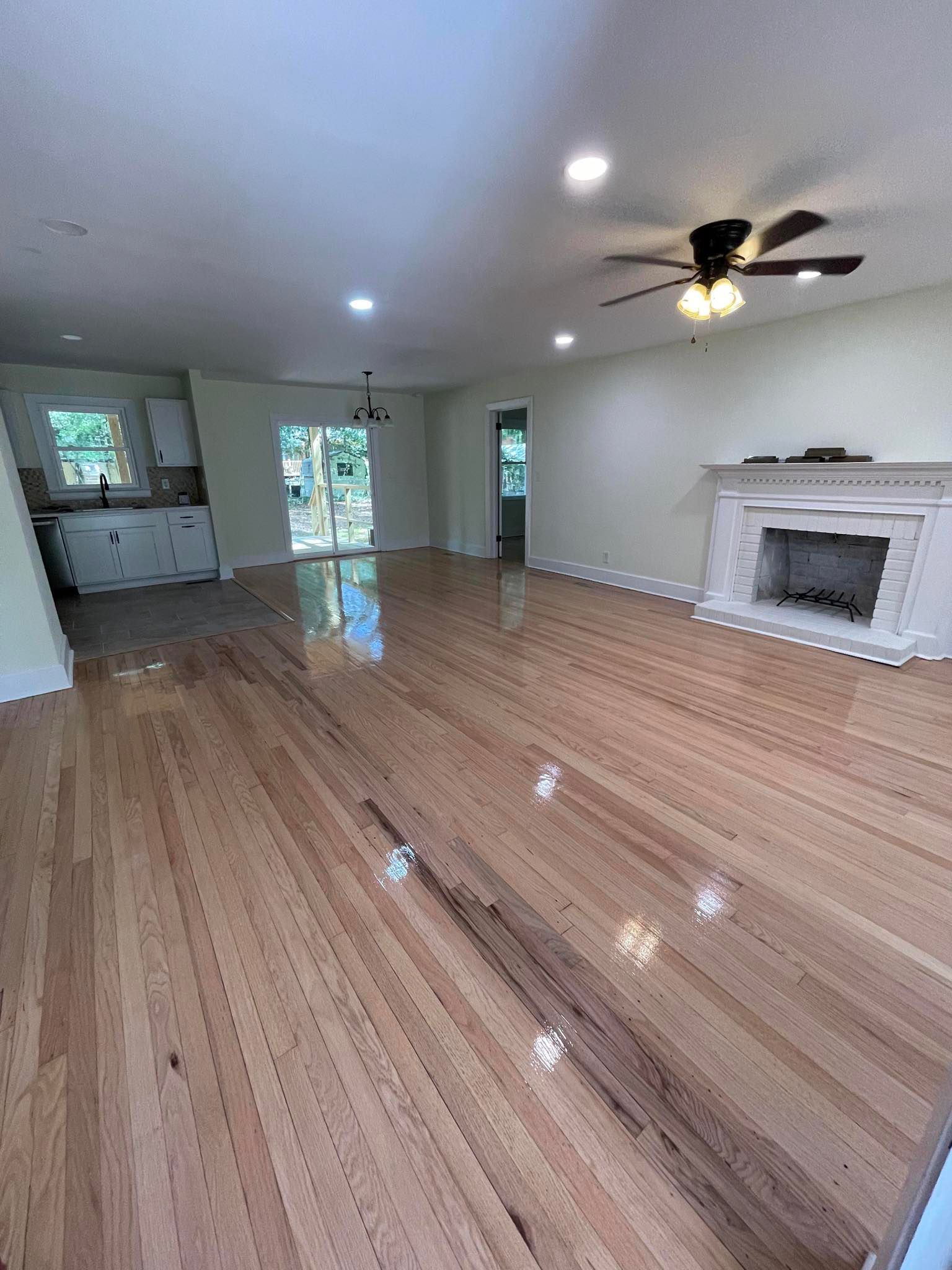 A living room with hardwood floors , a fireplace and a ceiling fan.