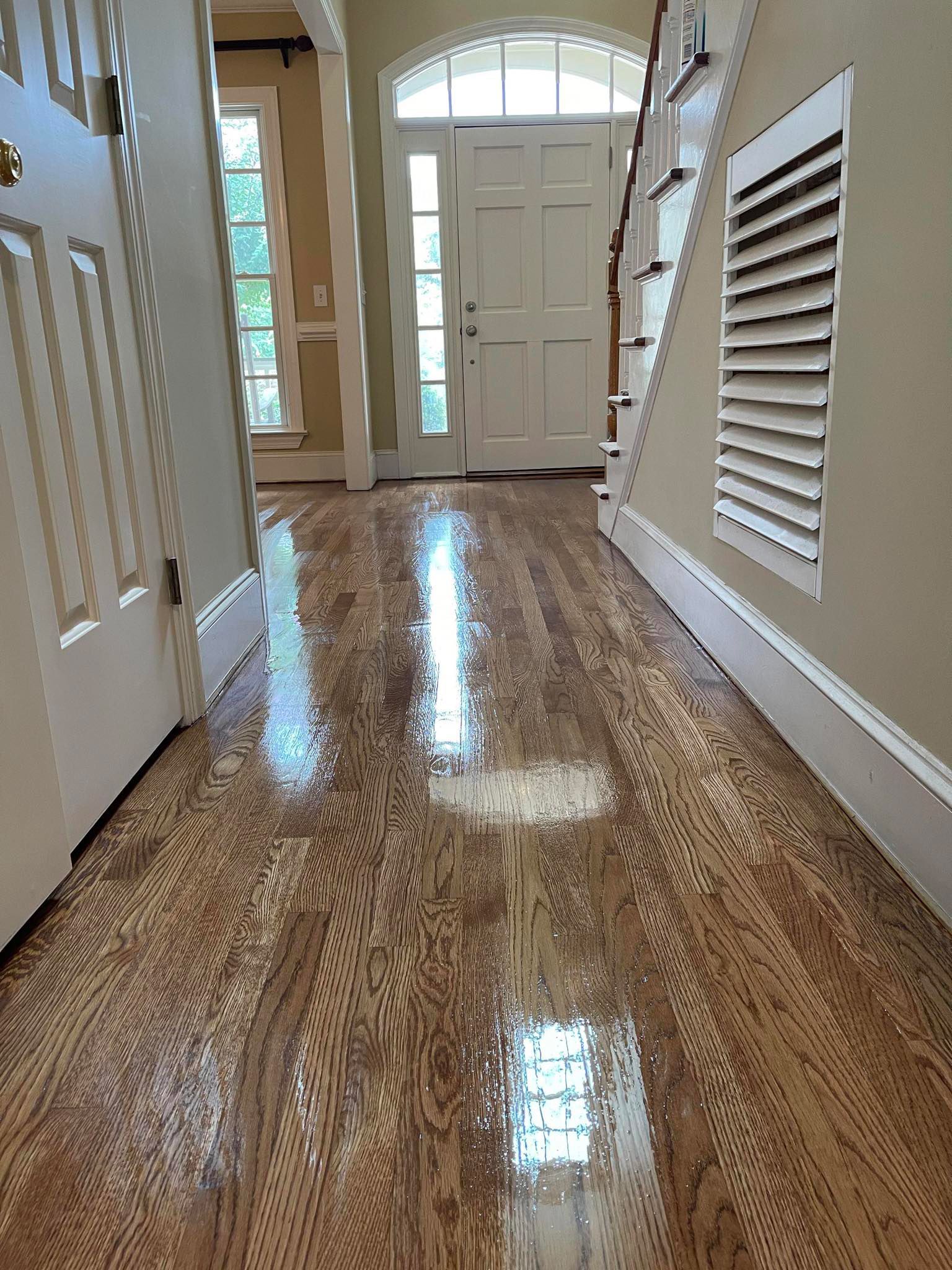 A hallway with a wooden floor and stairs in a house.