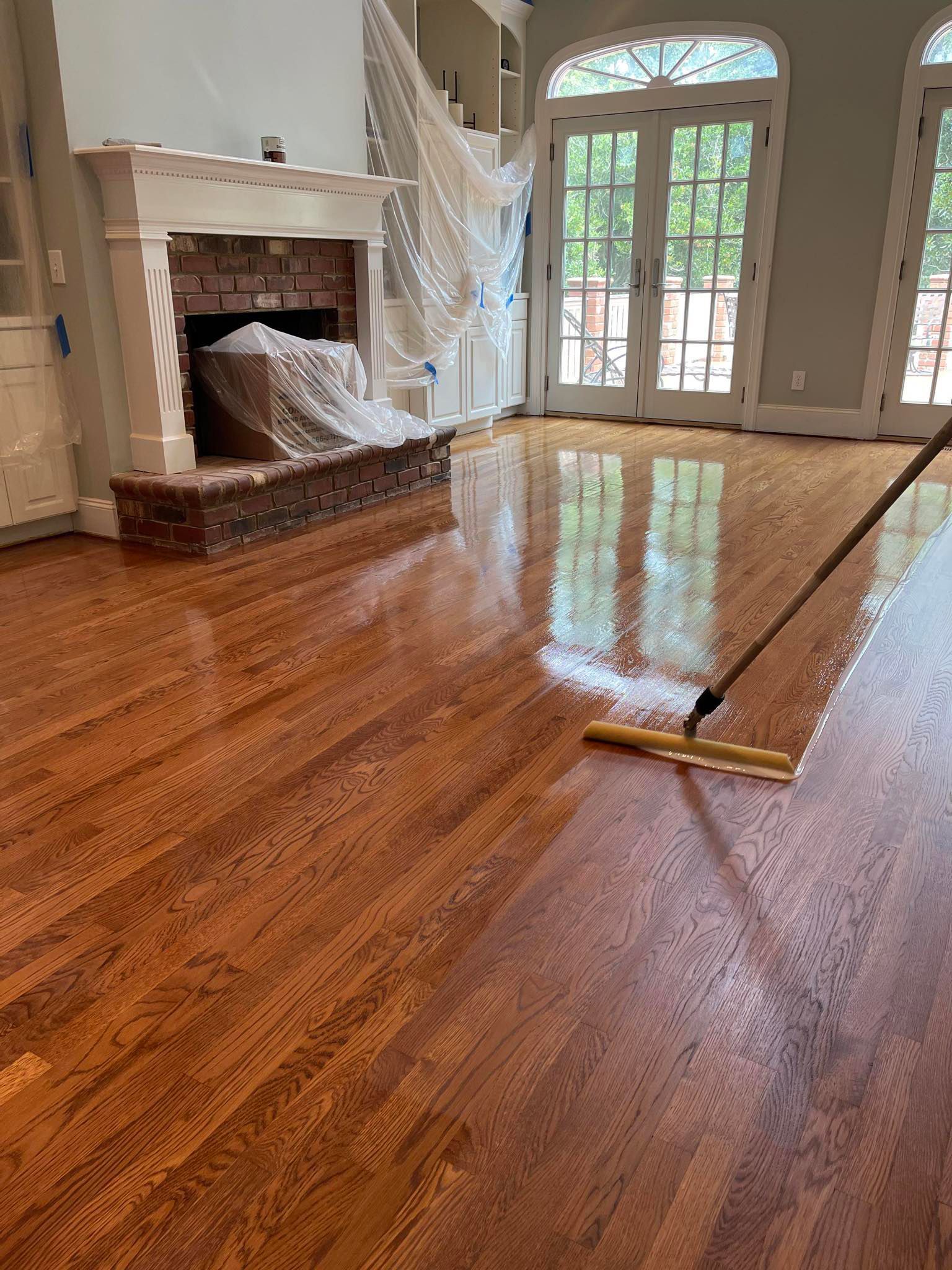 A person is polishing a wooden floor in a living room.