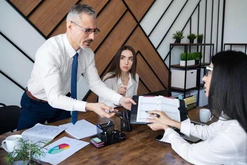 Business meeting in an office, with documents, charts, and a camera on the table.
