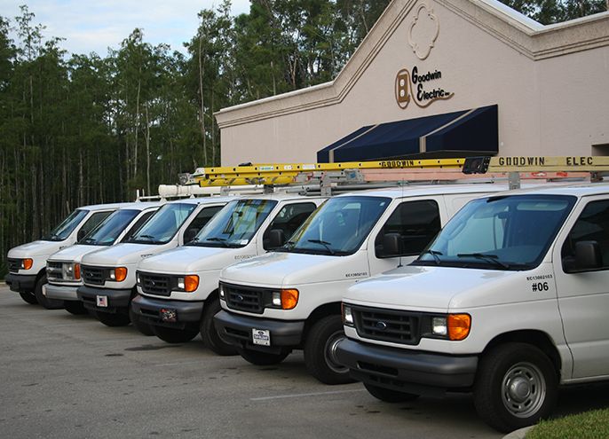 A row of white vans parked in front of a building.