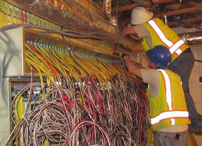 Two men are working on a bunch of wires.