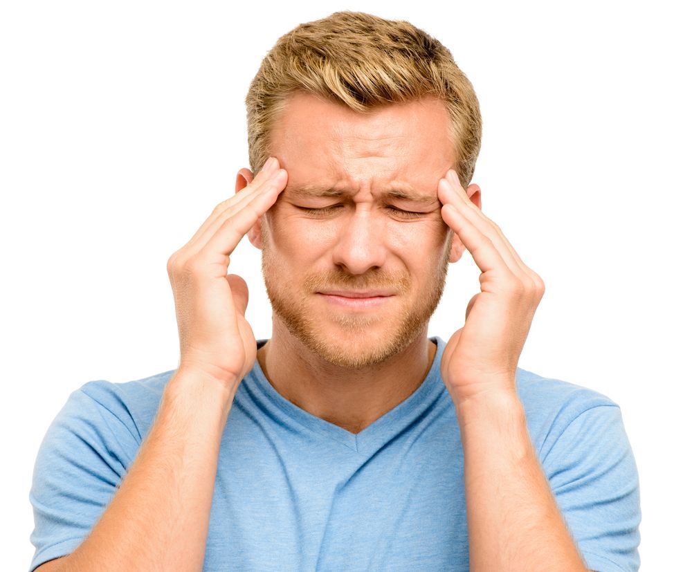 Man in blue shirt pressing temples with eyes closed, showing a headache or stress