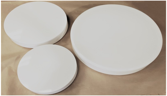 Three white round foam disks on a tan surface, arranged in varying sizes.