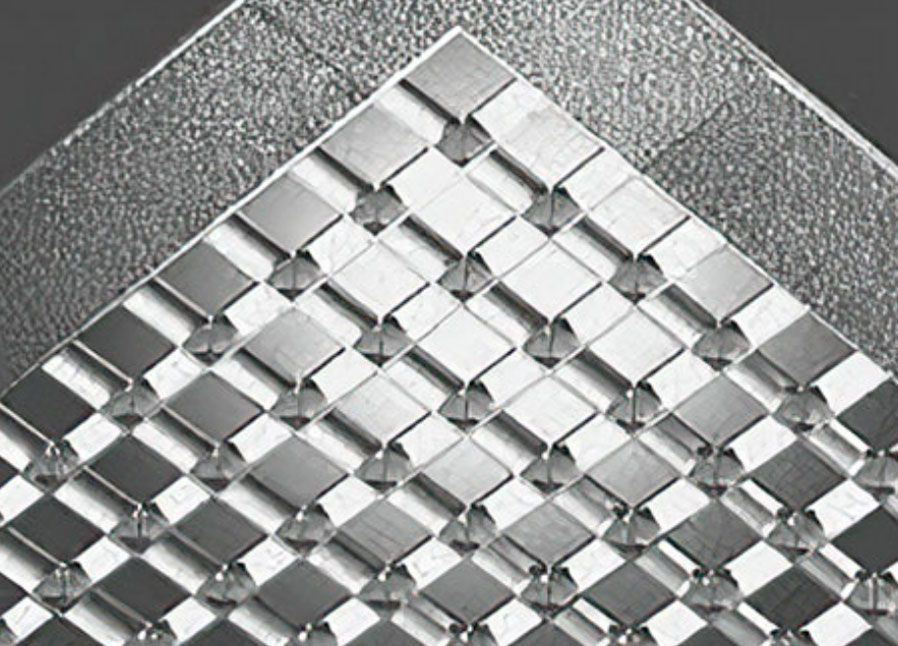 Close-up of a silver woven metallic pattern with a diamond grid on a textured gray background