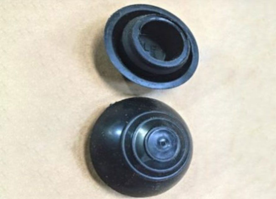 Two black plastic circular parts on a beige surface, one above the other