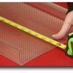 Yellow tape measure measuring a clear plastic sheet on a red work surface