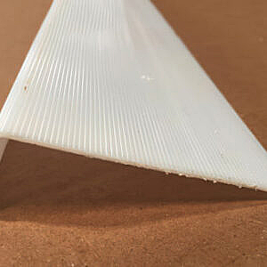 White ribbed plastic cone on a brown surface