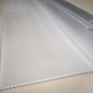 White woven mesh fabric roll on a beige surface, viewed close up from an angle