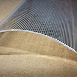 Close-up of a ribbed gray metal surface with a tan curved edge in the foreground