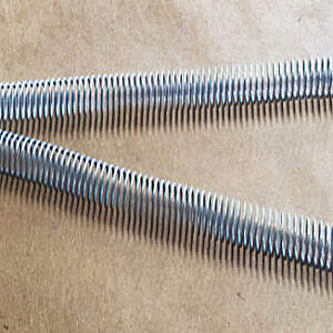 Two silver corrugated hoses crossing on a tan surface.