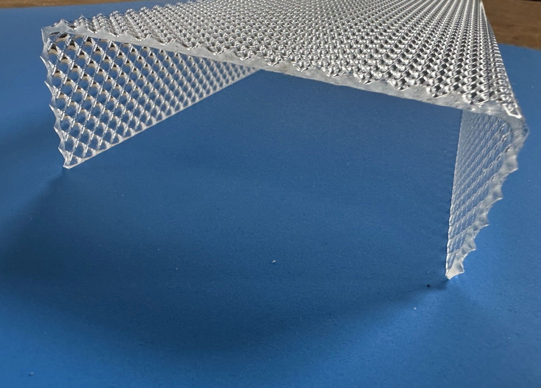 Silver textured metal table or shelf with an angled front edge on a blue background