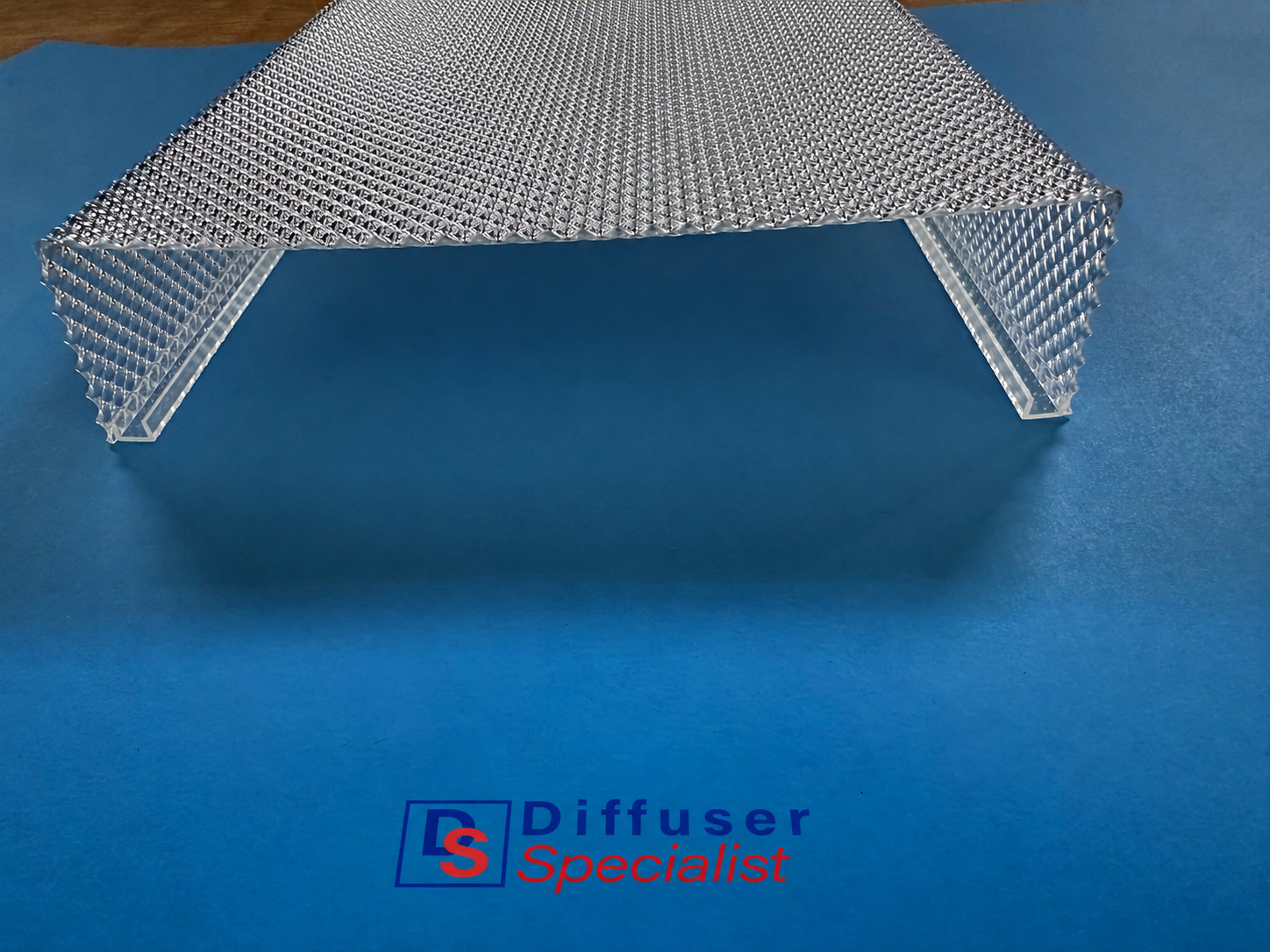 White patterned plastic diffuser panel on a blue background with a Diffuser Specialties logo below
