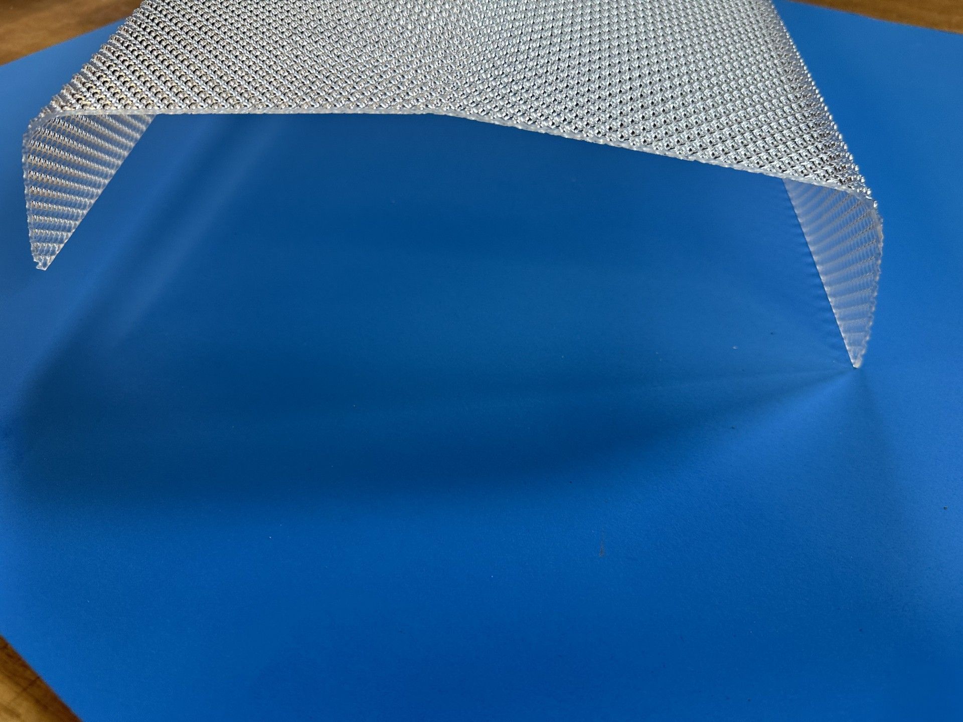 Blue surface under a silver textured curved canopy against a plain background