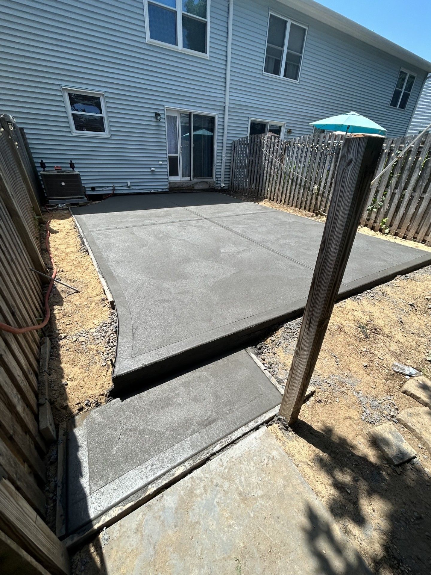 A concrete patio is being built in the backyard of a house.