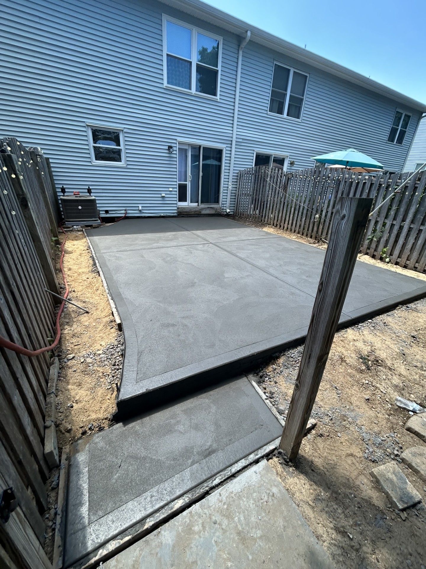 A concrete patio is being built in the backyard of a house.