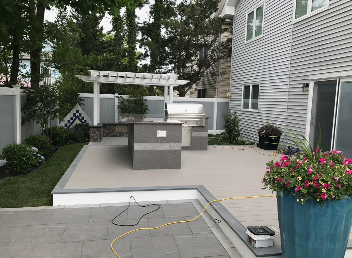 A patio with a grill and a blue pot of flowers