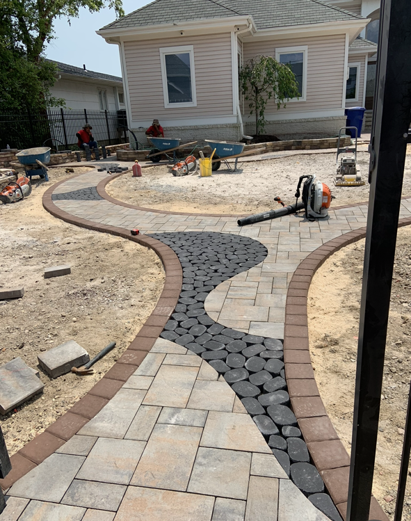A brick walkway is being built in front of a house.