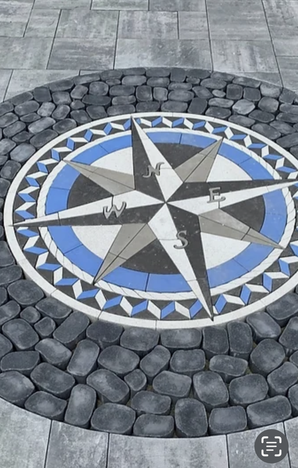 A blue and white compass on a brick pavement
