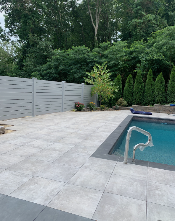 A swimming pool with a fence surrounding it and trees in the background