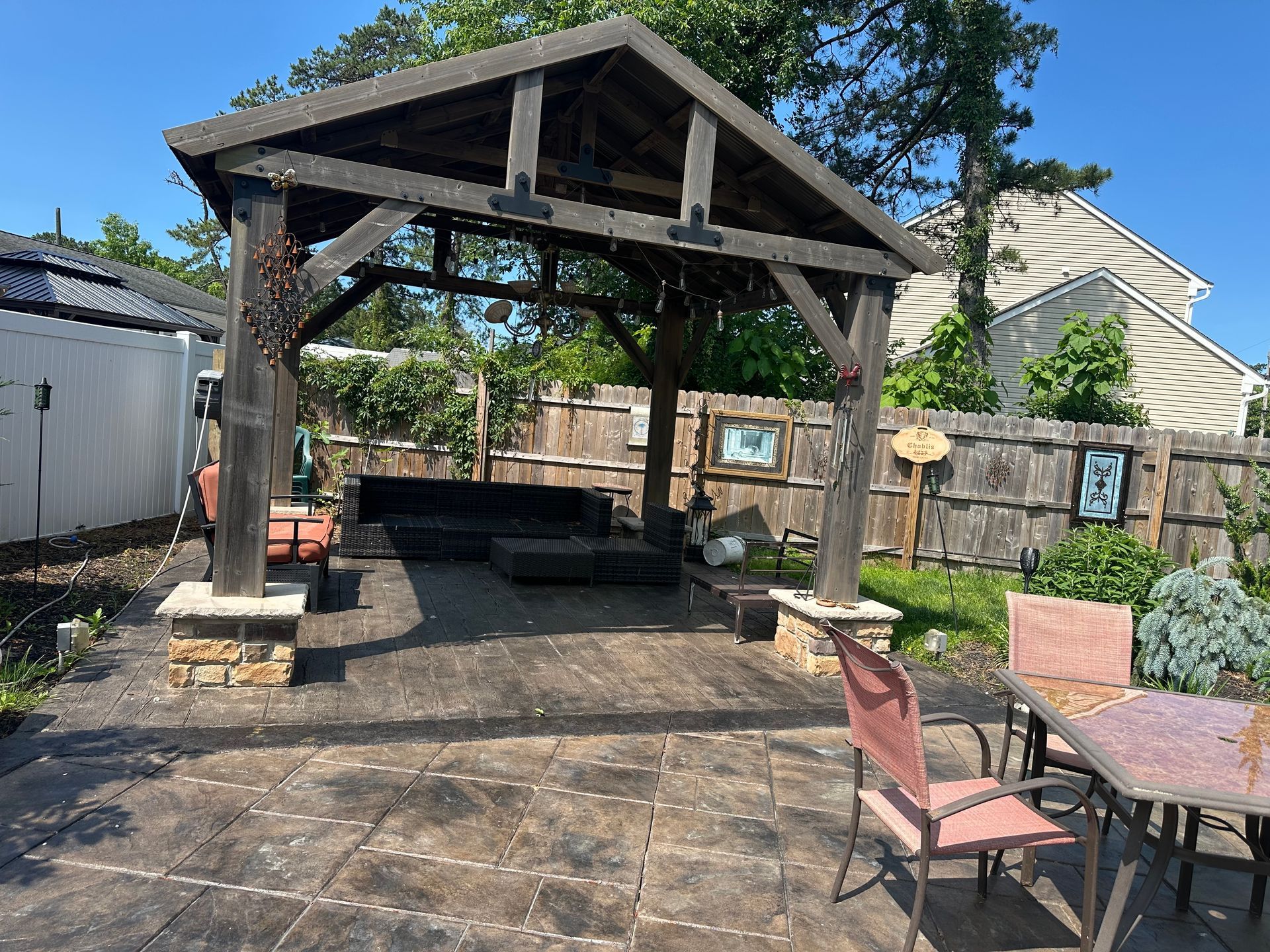 There is a gazebo in the backyard with a table and chairs underneath it.