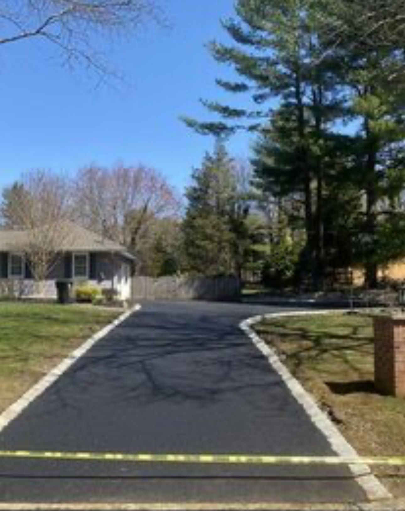 A driveway leading to a house with trees in the background.