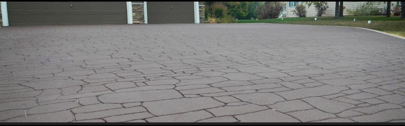 A brick driveway with a fence in the background.